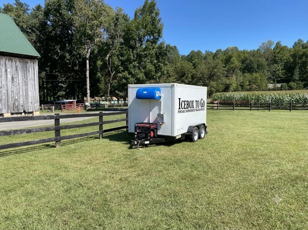 A clean, modern mobile refrigerated trailer parked outside an event venue, showcasing accessible cold storage solutions for caterers.